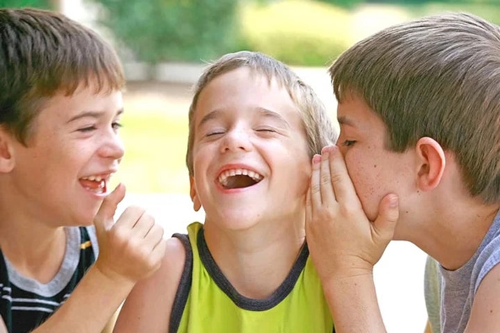 kids laughing and talking to each other outside.