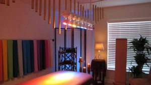 massage therapy table bed with windwchimes and lights rainbow colors above it.