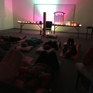 People laying in the dark with colored lights and meditating.