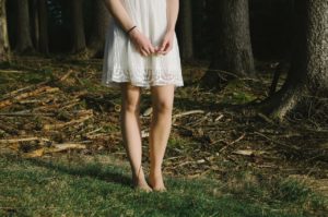 white sundress on a lady barefooted in the woods.