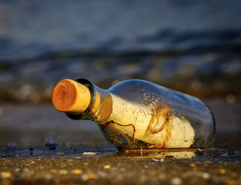A glass bottle with a message in It on the beach .