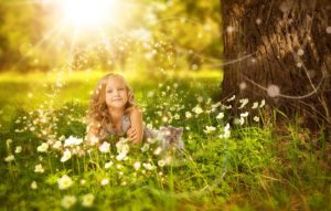 A little girl next to a car in a meadow next to a tree and light burst, whimsical flowers.
