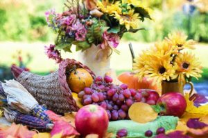 Harvest table spread with cornucopia and various fruits and flowers.