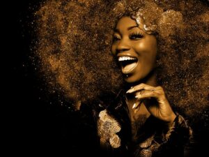 A lday with an afro and sparkley glitter surrounding her and she's smiling.
